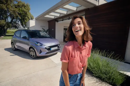 hyundai i10 außenansicht frau steht neben dem auto und lacht